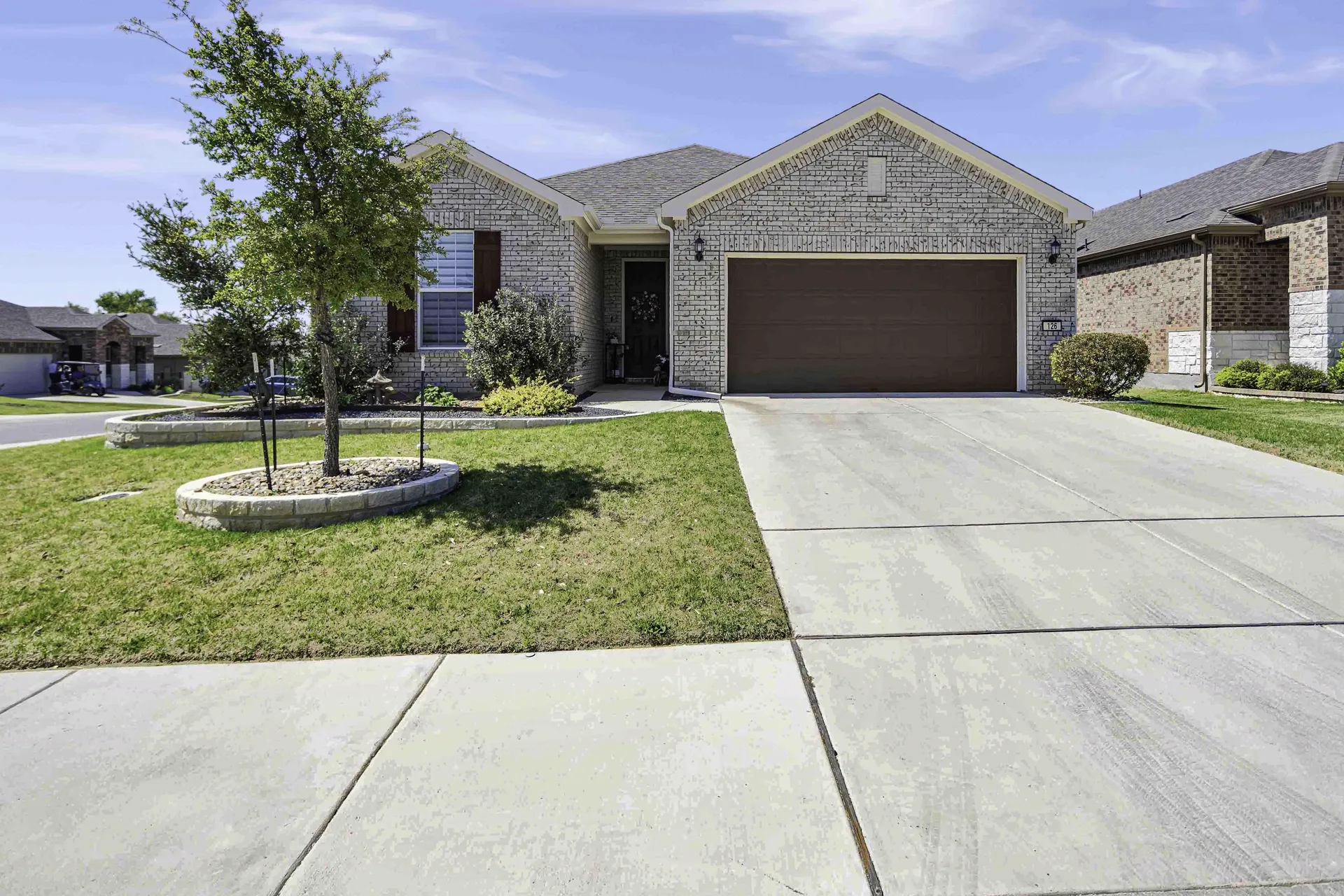 Front exterior with stone facade, 2-car garage and manicured lawn