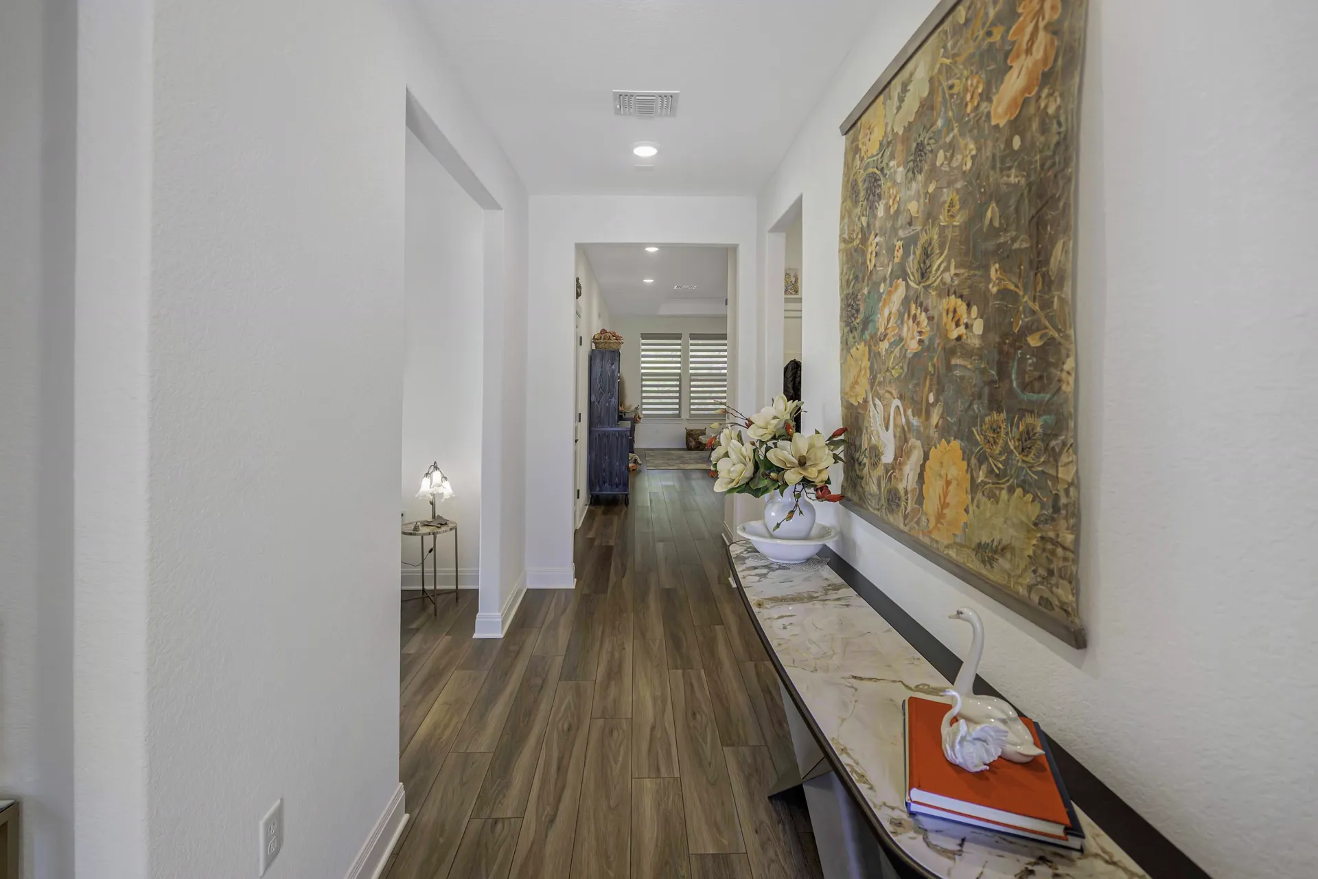 Entry foyer with hardwood floors, art and warm lighting