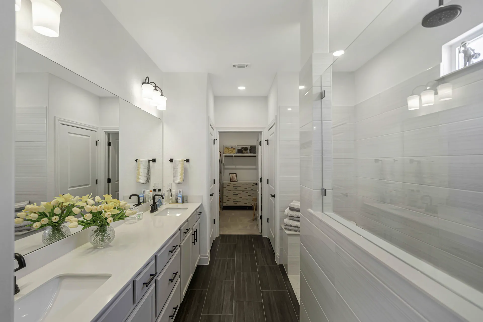 Primary bathroom with dual vanity, white countertops and modern fixtures