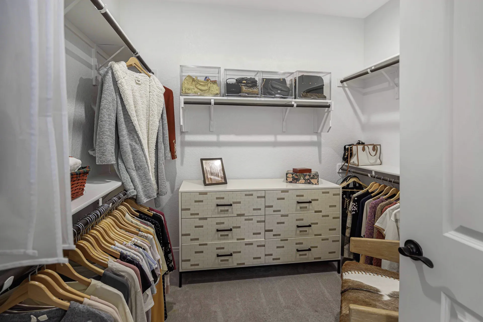 Primary closet — full view with clothes and island dresser